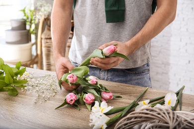 Photo of Male decorator creating beautiful bouquet at table