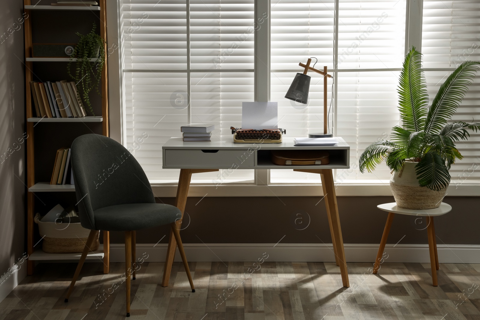 Photo of Comfortable writer's workplace interior with typewriter on desk in front of window