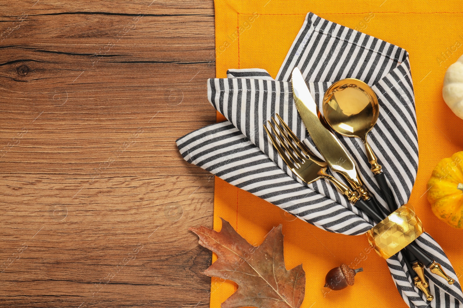 Photo of Cutlery, napkin and dry leaf on wooden background, flat lay with space for text. Table setting