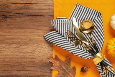 Cutlery, napkin and dry leaf on wooden background, flat lay with space for text. Table setting