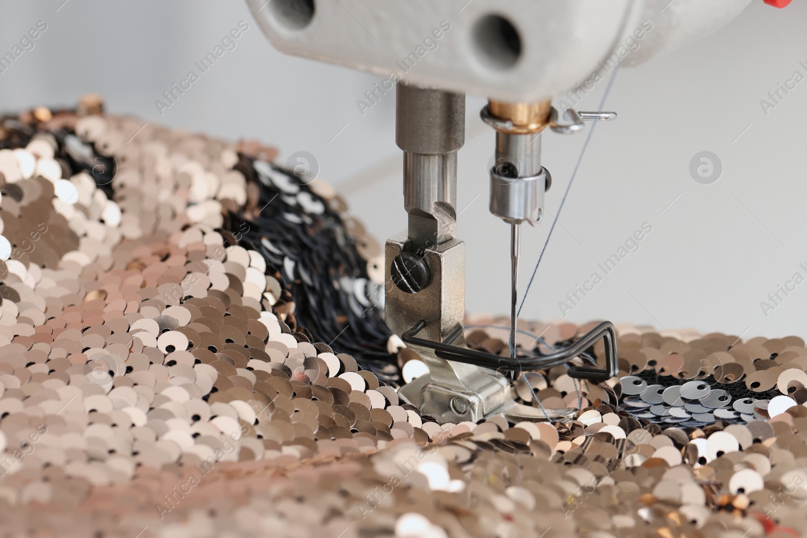 Photo of Sewing machine and beautiful fabric with paillettes indoors, closeup