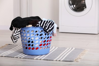 Photo of Plastic laundry basket overfilled with clothes in bathroom. Space for text