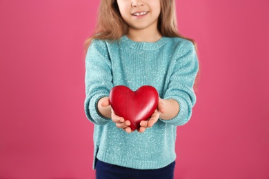 Girl with decorative heart on color background, closeup