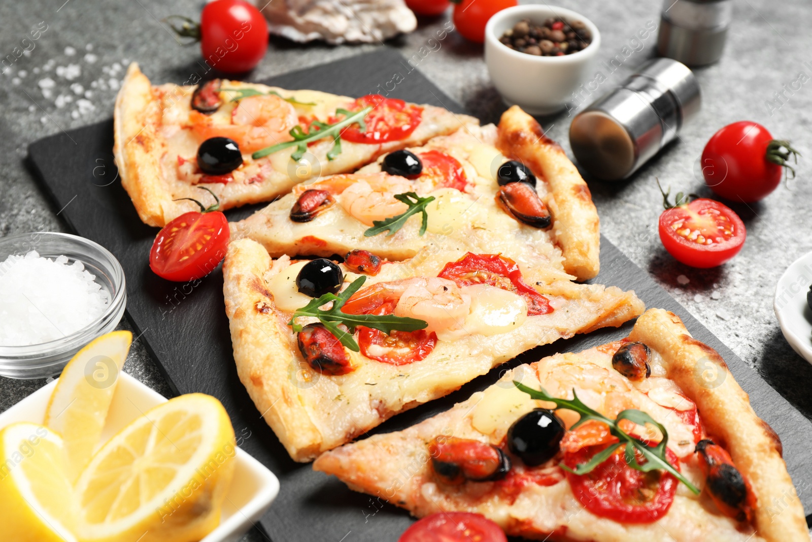 Photo of Tasty pizza with seafood and ingredients on grey table, closeup