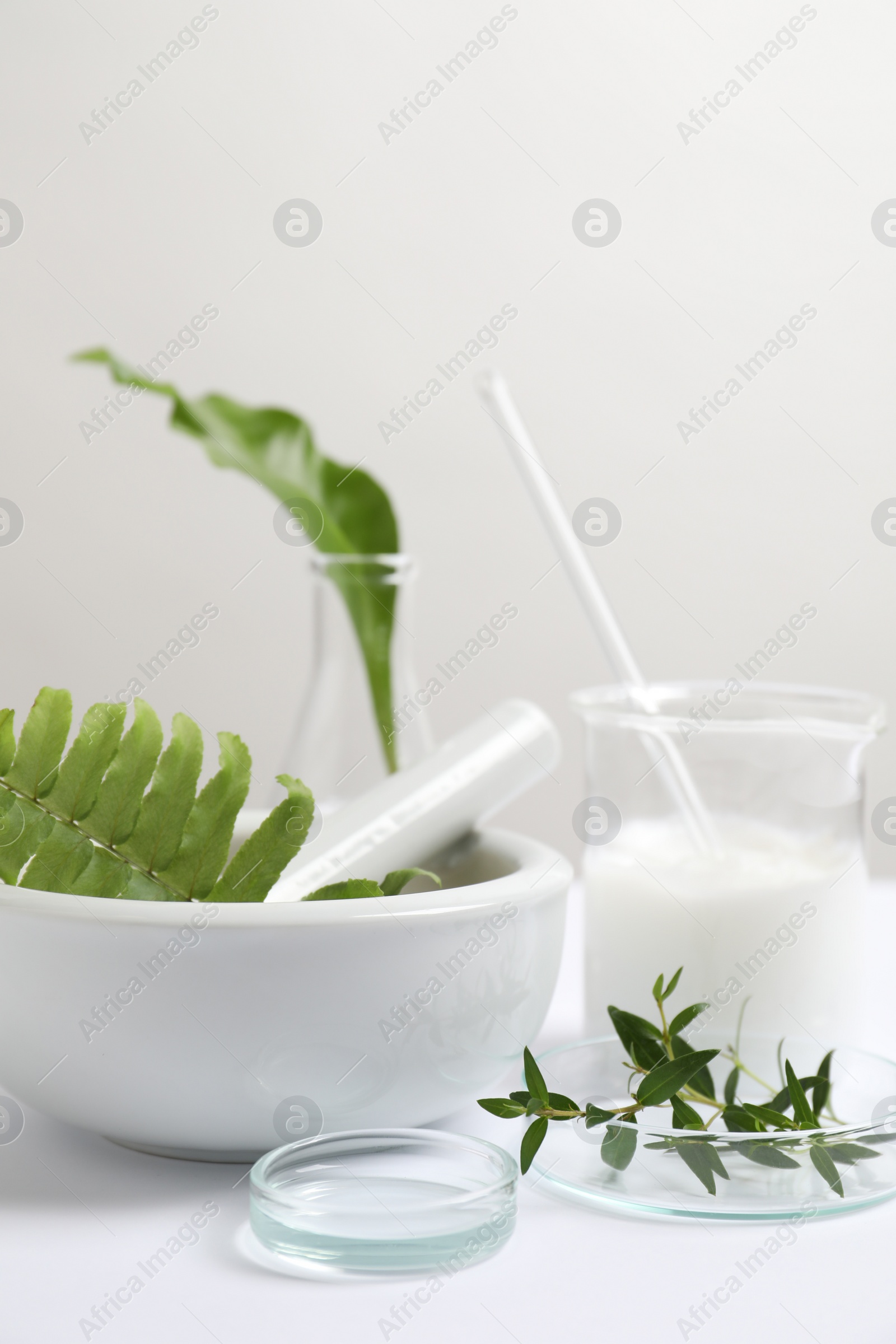 Photo of Natural ingredients and laboratory glassware for organic cosmetic product on white table