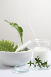 Natural ingredients and laboratory glassware for organic cosmetic product on white table