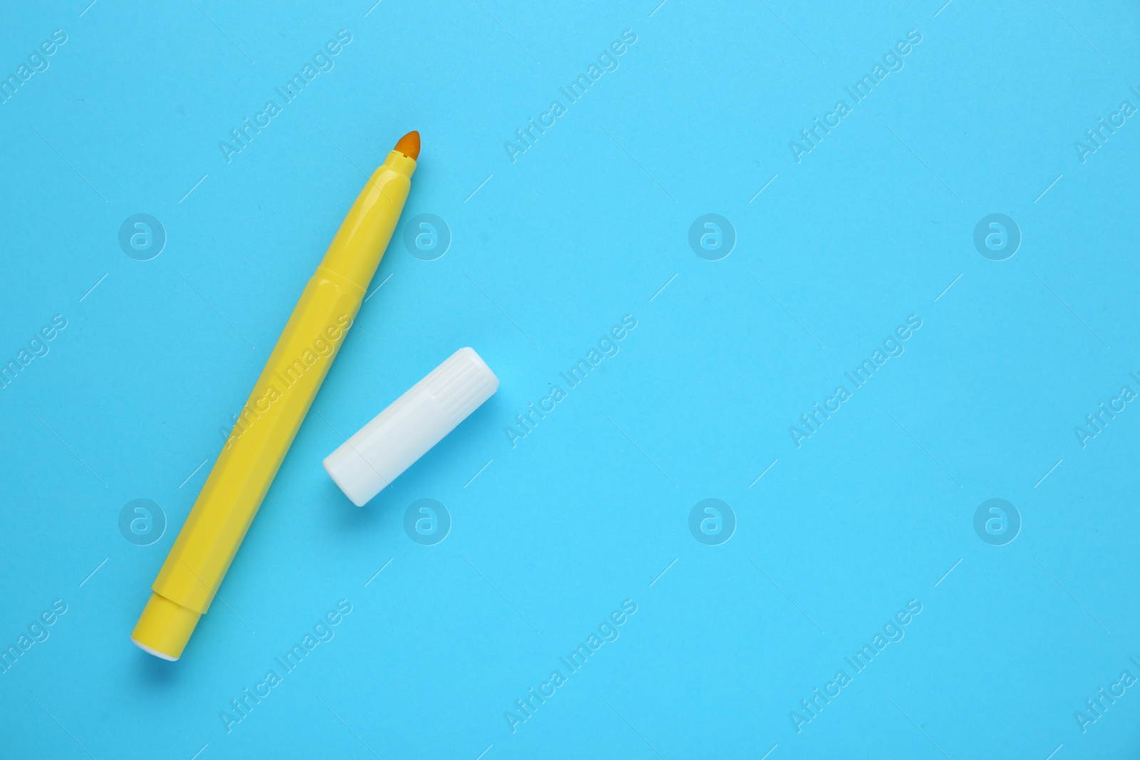 Photo of Bright yellow marker and cap on light blue background, flat lay. Space for text