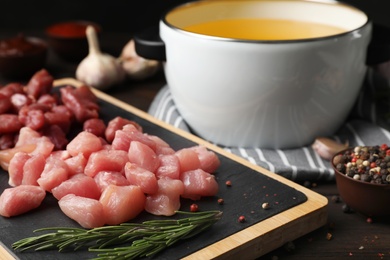 Board with raw meat fondue pieces and rosemary on table