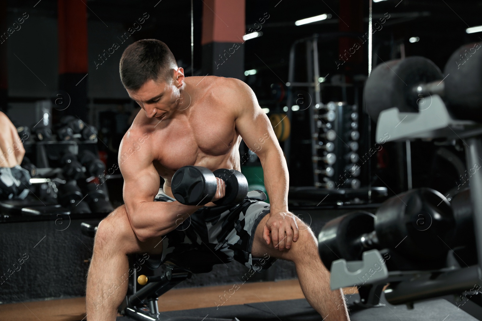 Photo of Man working out with dumbbell in modern gym