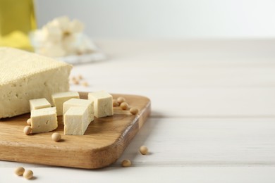 Photo of Cut tofu and soya beans on white wooden table. Space for text