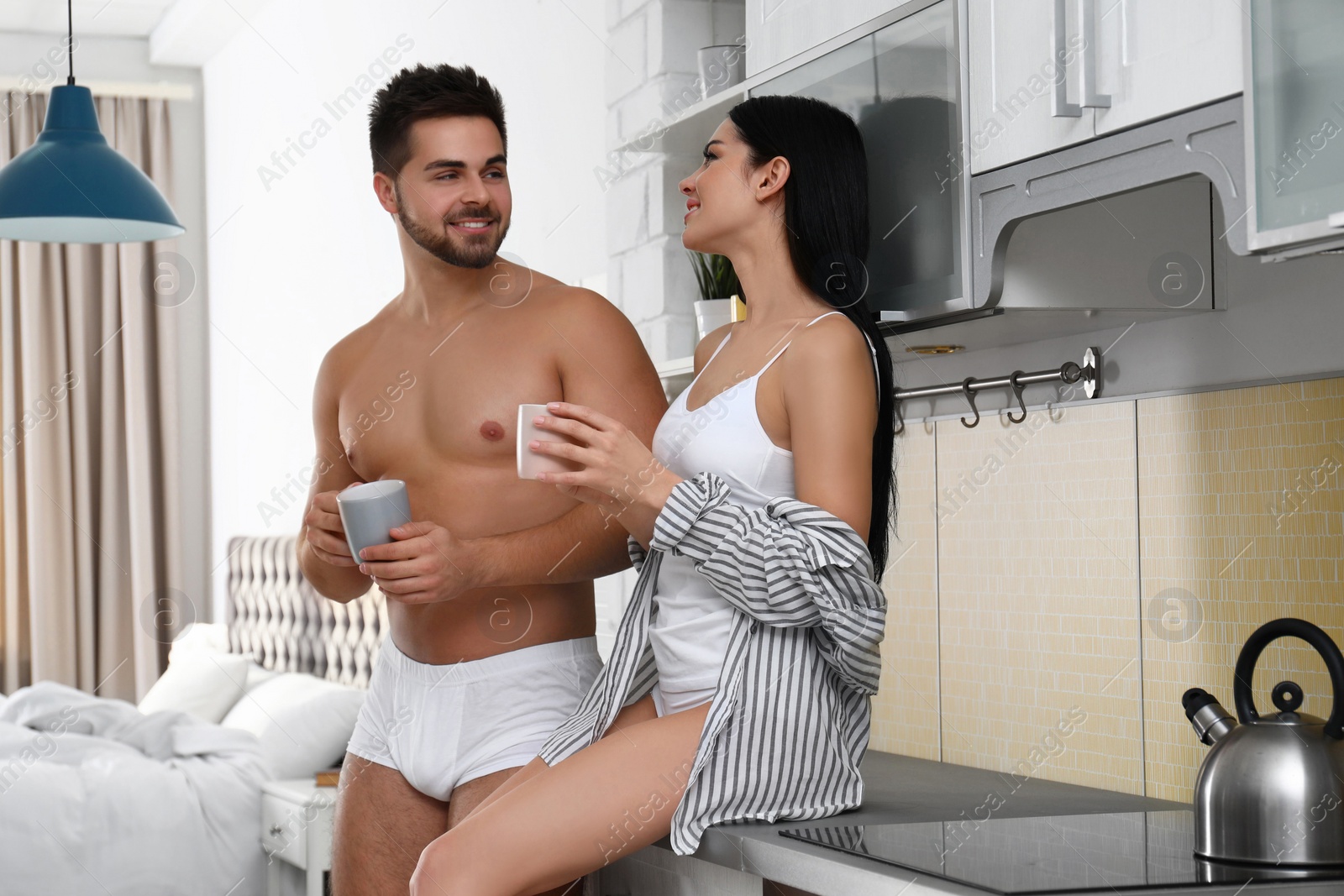 Photo of Young couple in white underwear drinking coffee at home