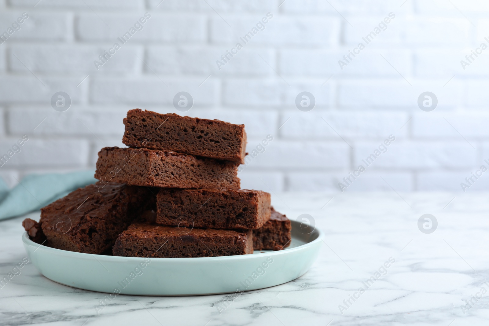 Photo of Delicious chocolate brownies on white marble table. Space for text