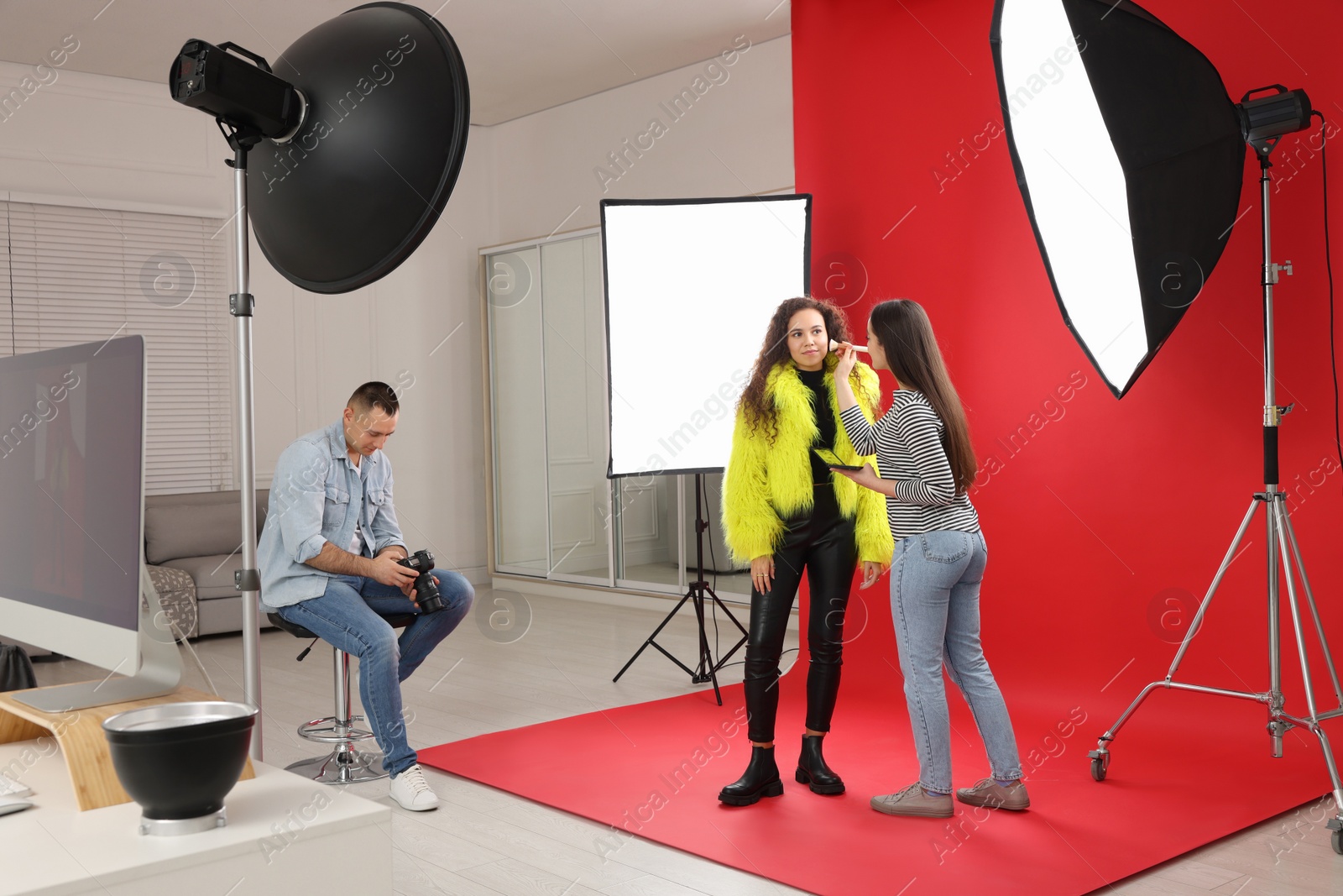 Photo of Professional photographer and makeup artist with model in studio