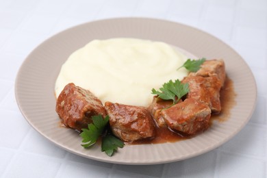 Delicious goulash with mashed potato on white tiled table, closeup