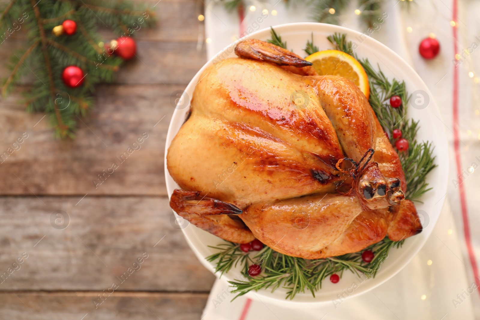 Photo of Platter of cooked turkey with garnish and Christmas decoration on wooden background, top view. Space for text