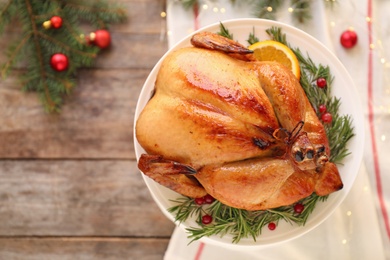 Platter of cooked turkey with garnish and Christmas decoration on wooden background, top view. Space for text