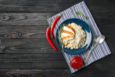 Photo of Delicious chicken risotto served on black wooden table, flat lay. Space for text