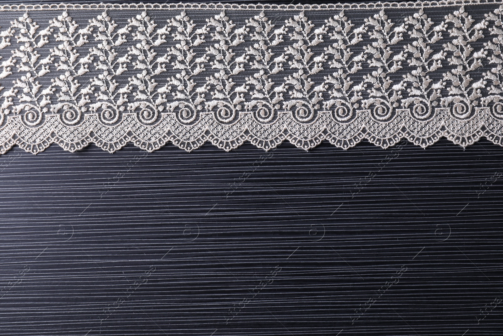 Photo of White lace on black table, top view. Space for text