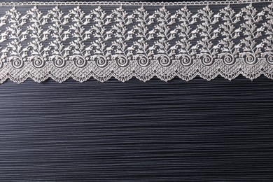 Photo of White lace on black table, top view. Space for text