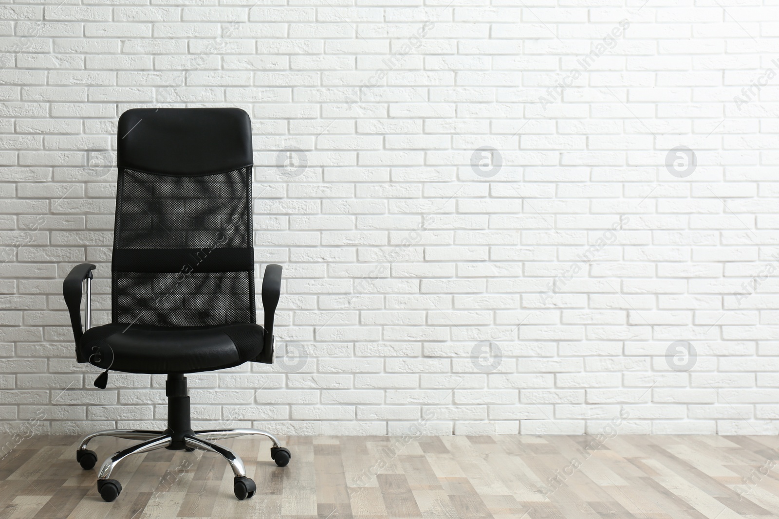 Photo of Comfortable office chair near white brick wall indoors. Space for text