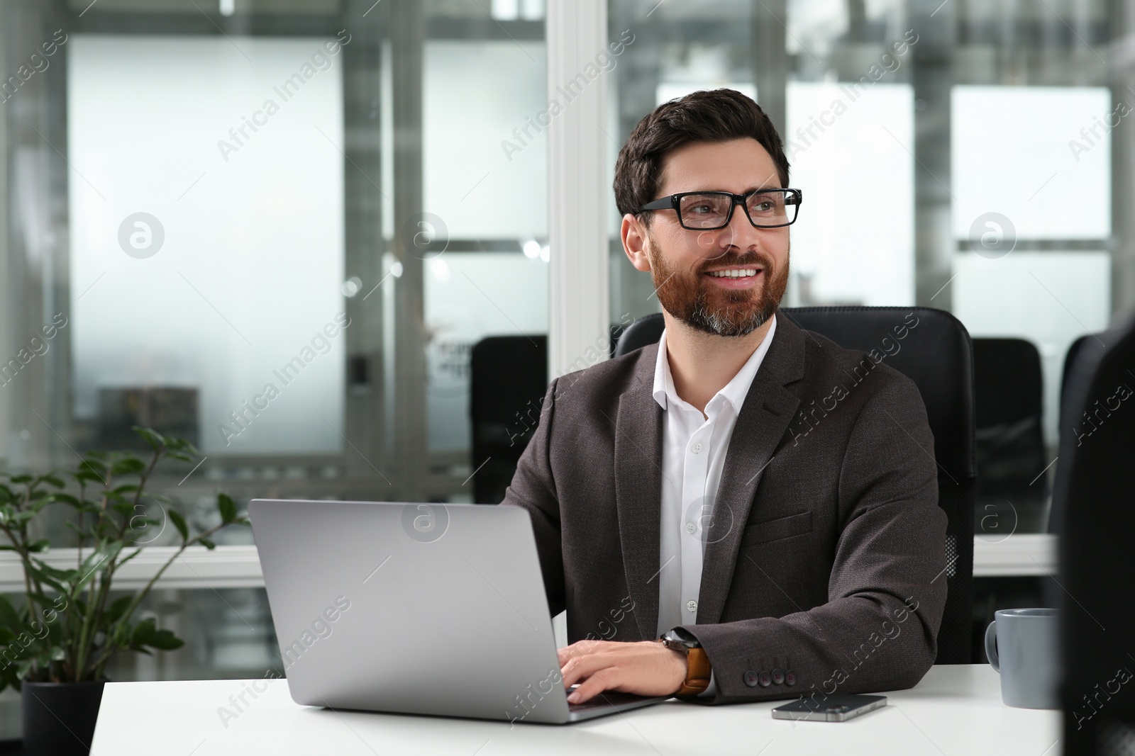 Photo of Man working on laptop at white desk in office. Space for text