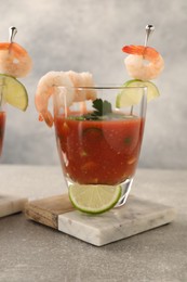 Photo of Tasty shrimp cocktail with sauce in glass and lime on light grey table