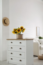 Beautiful yellow sunflowers on chest of drawers in room