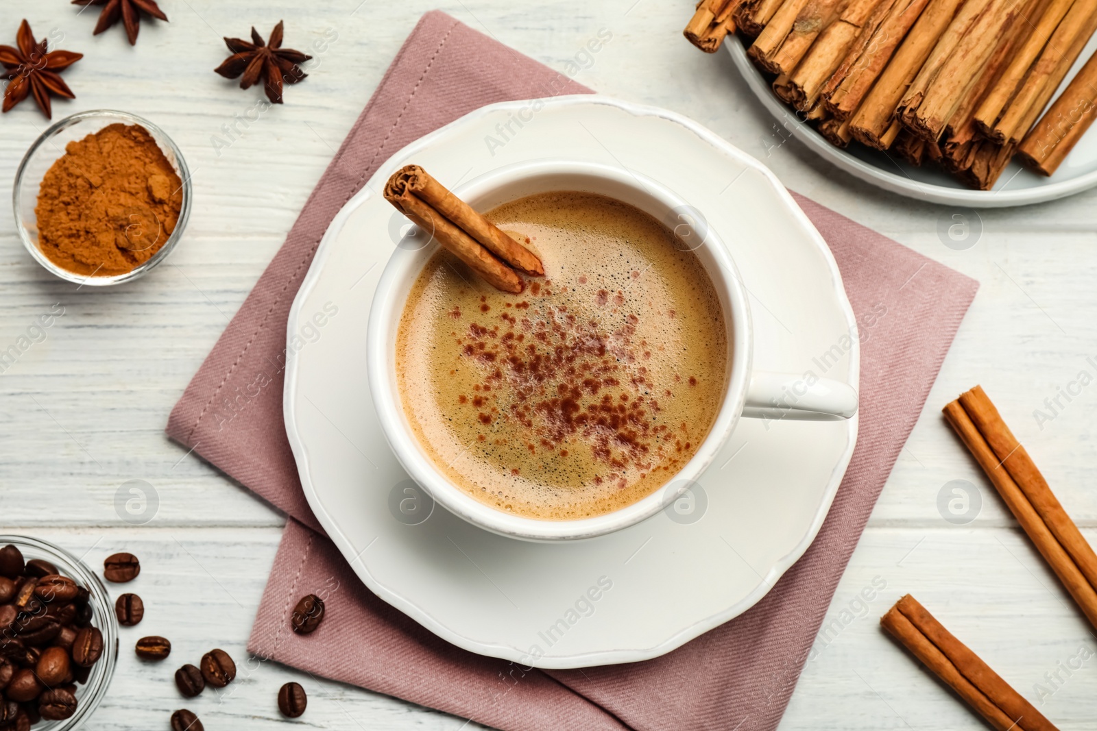 Photo of Delicious hot coffee with cinnamon on white wooden table, flat lay