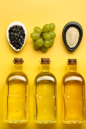 Vegetable fats. Different oils in glass bottles and ingredients on yellow table, flat lay