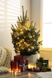 Beautiful Christmas tree and gift boxes in light room. Interior design