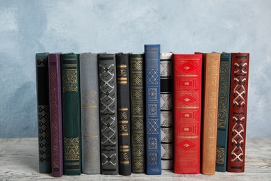 Stack of hardcover books on wooden table against light blue background