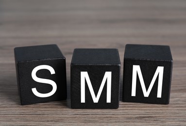 Photo of Cubes with abbreviation SMM (Social media marketing) on wooden table
