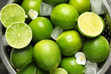 Colander with fresh ripe limes and ice cubes, closeup