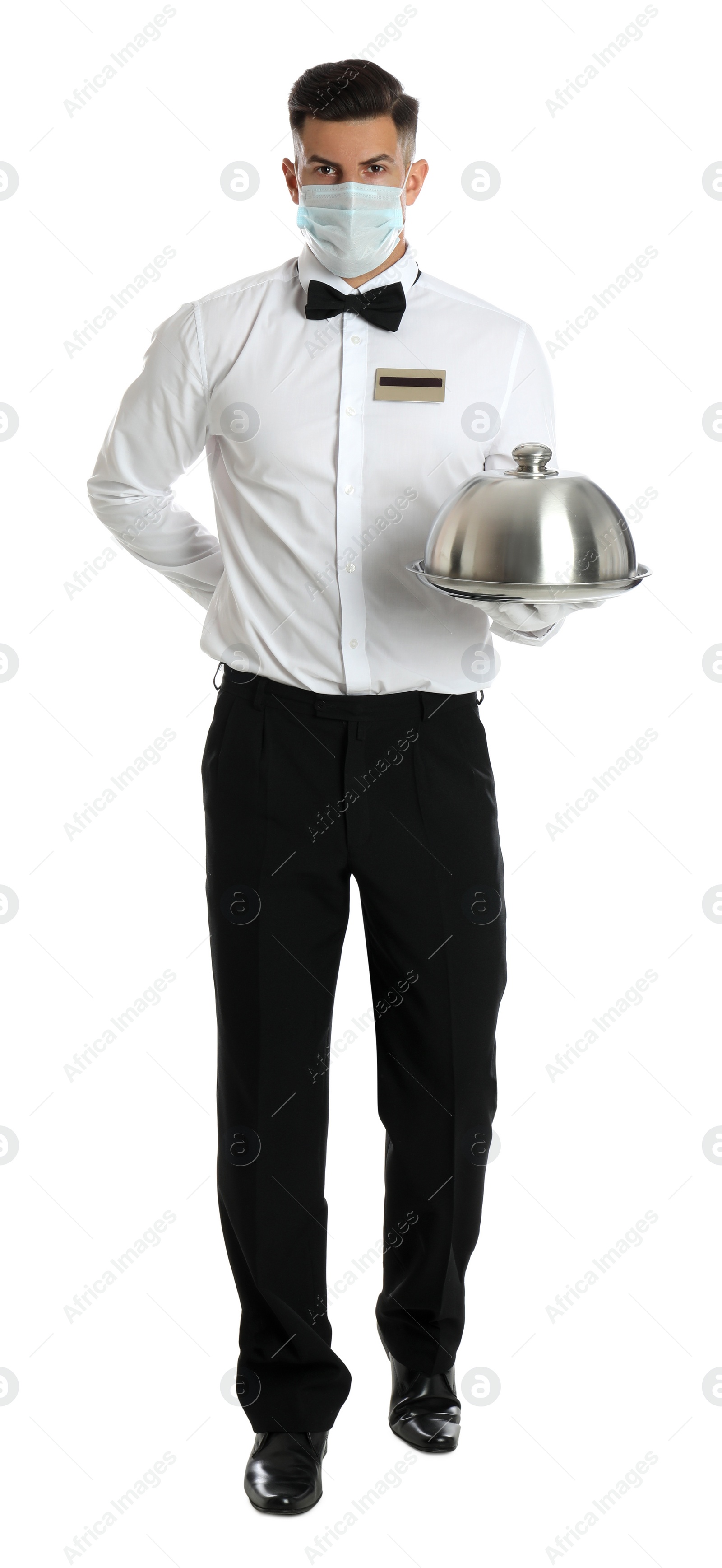 Photo of Waiter in medical face mask holding tray with lid on white background