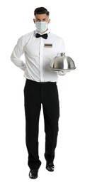 Photo of Waiter in medical face mask holding tray with lid on white background