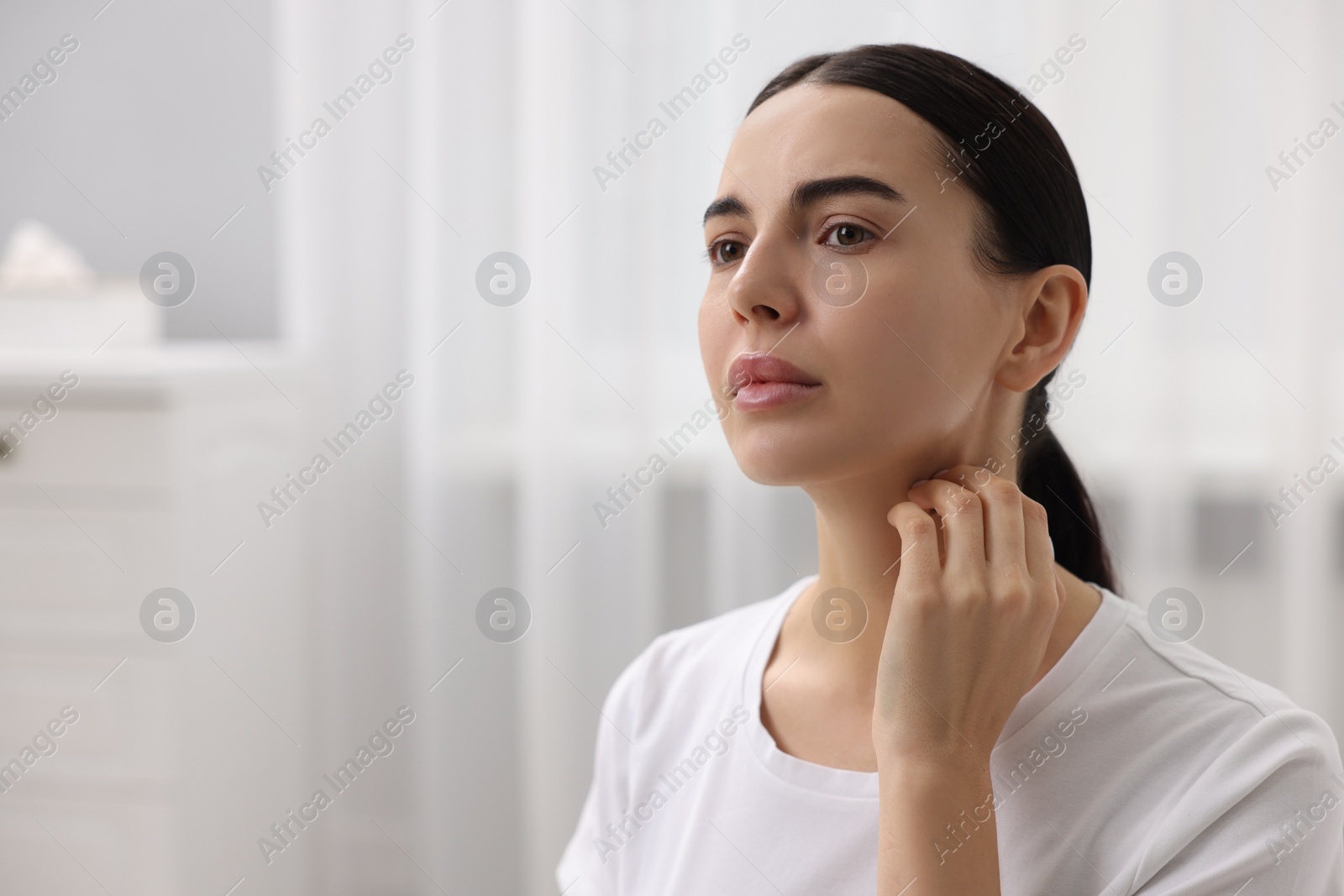 Photo of Woman with dry skin checking her face indoors, space for text