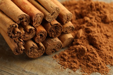 Photo of Cinnamon sticks and powder on wooden table, closeup