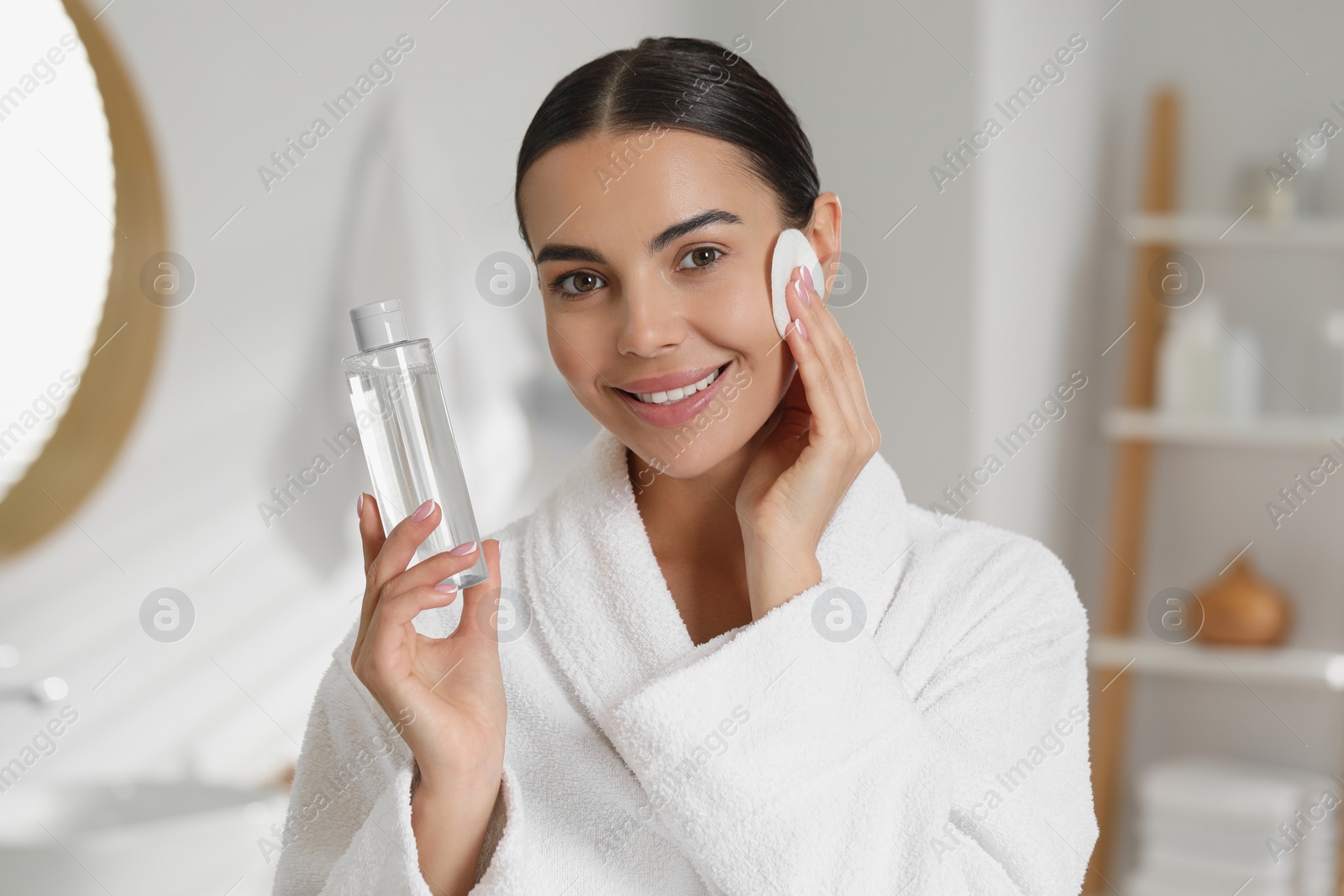 Photo of Beautiful woman removing makeup with cotton pad in bathroom