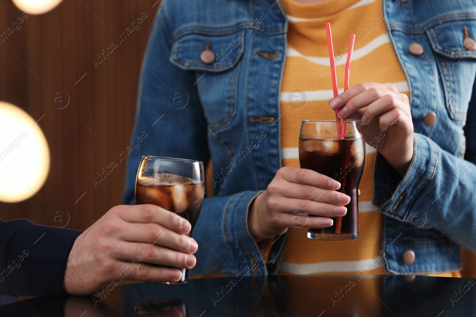 Photo of People holding glasses of cola with ice on blurred background, closeup