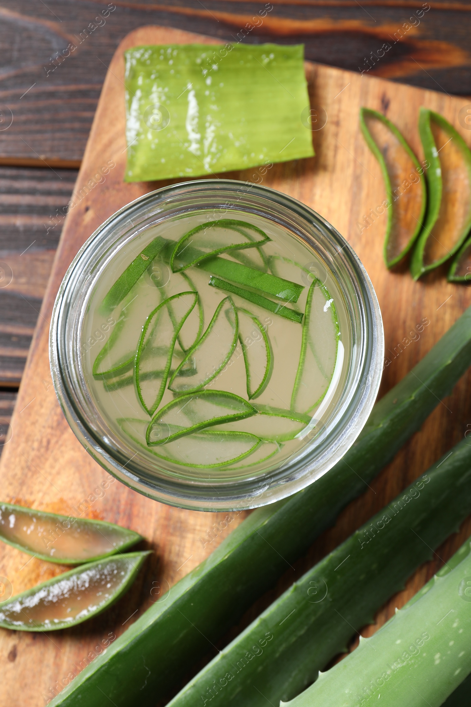 Photo of Fresh aloe juice in jar and leaves on wooden table, top view