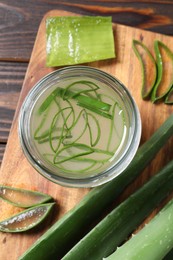 Photo of Fresh aloe juice in jar and leaves on wooden table, top view