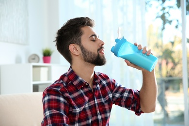 Photo of Young man drinking protein shake at home