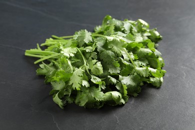 Photo of Bunch of fresh green cilantro on black table, closeup
