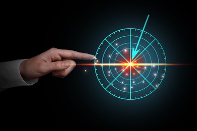 Businessman pointing at virtual screen with digital target against dark background, closeup