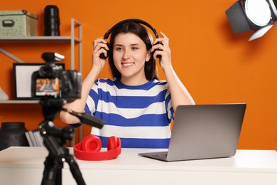 Photo of Smiling technology blogger wearing headphones while recording video at home