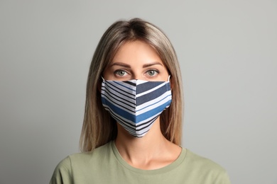Young woman in protective face mask on light grey background