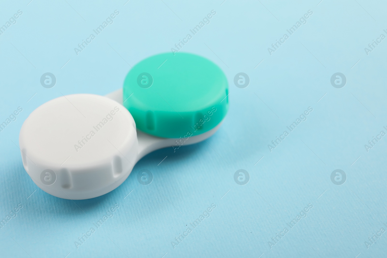 Photo of Case with color contact lenses on light blue background. Space for text