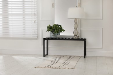 Console table with lamp, bouquet of green branches and mirror in room. Interior design