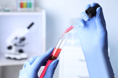 Photo of Assistant dripping sample into test tube at chemistry laboratory, closeup