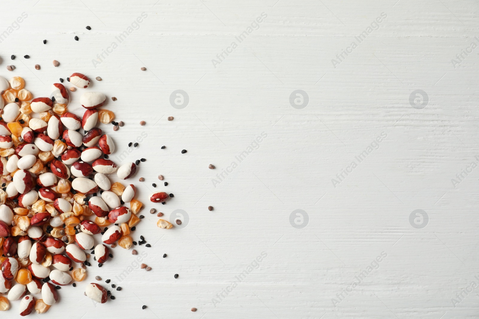 Photo of Mixed vegetable seeds on white wooden background, flat lay. Space for text